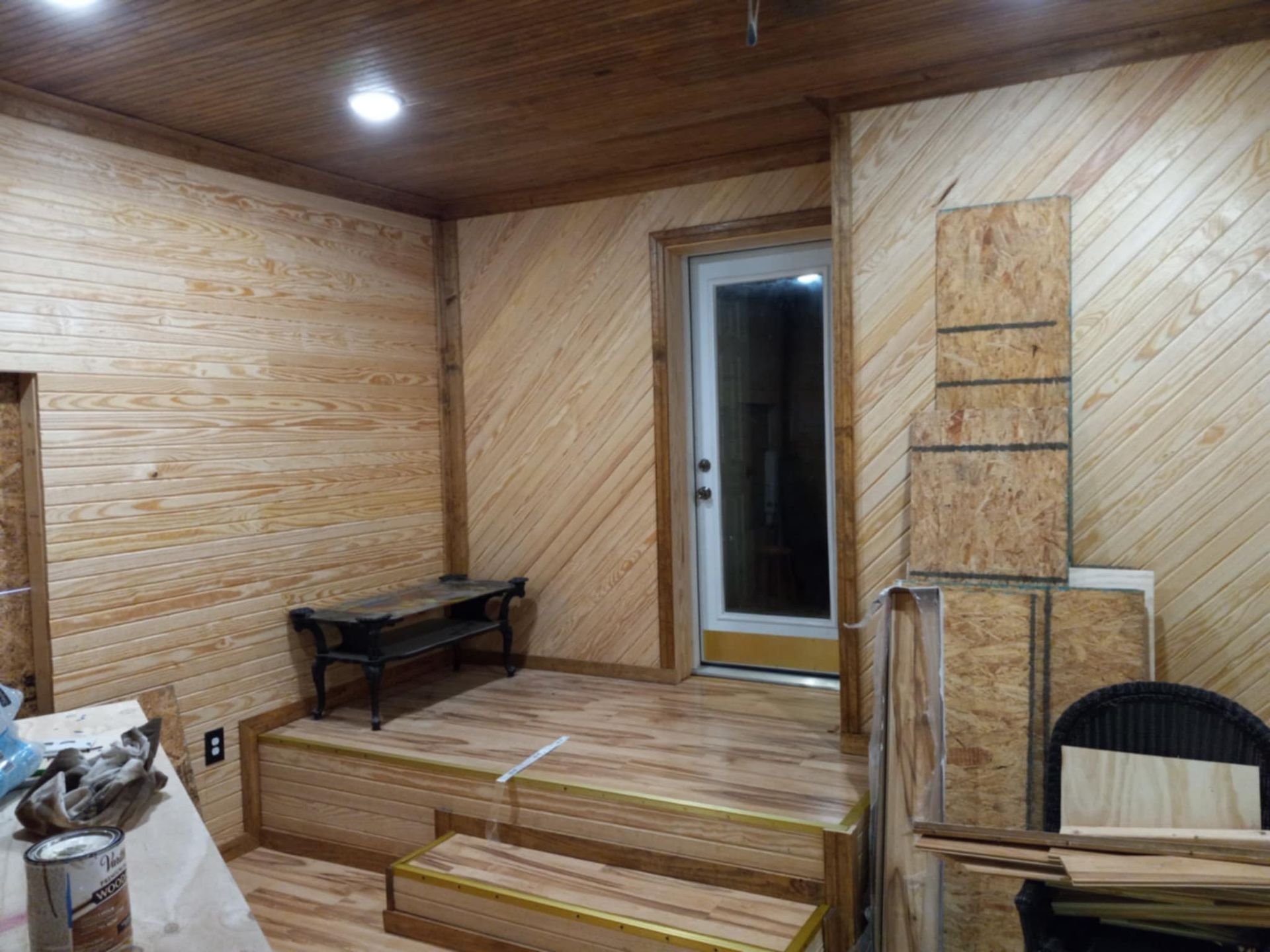 Interior room with wood paneling, door, and small built-in platform with steps.