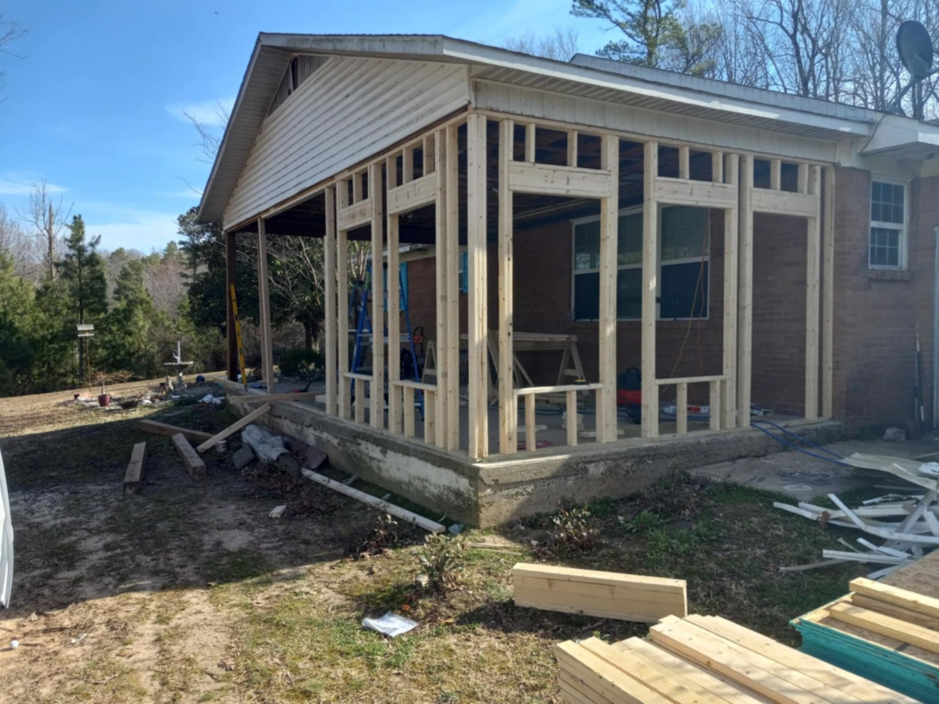 A house with a sunroom addition under construction, wooden frame visible.