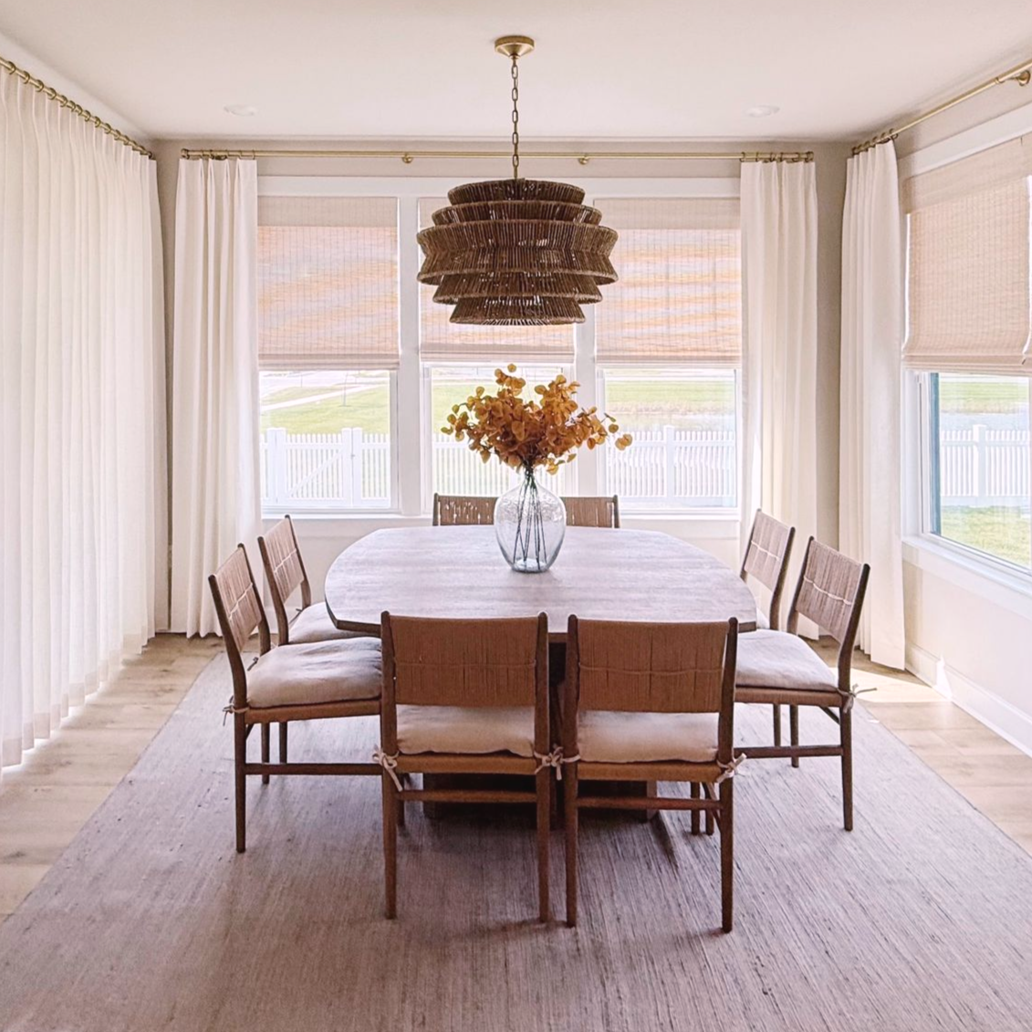 Pinch pleat drapes in dining room with woven wood shades