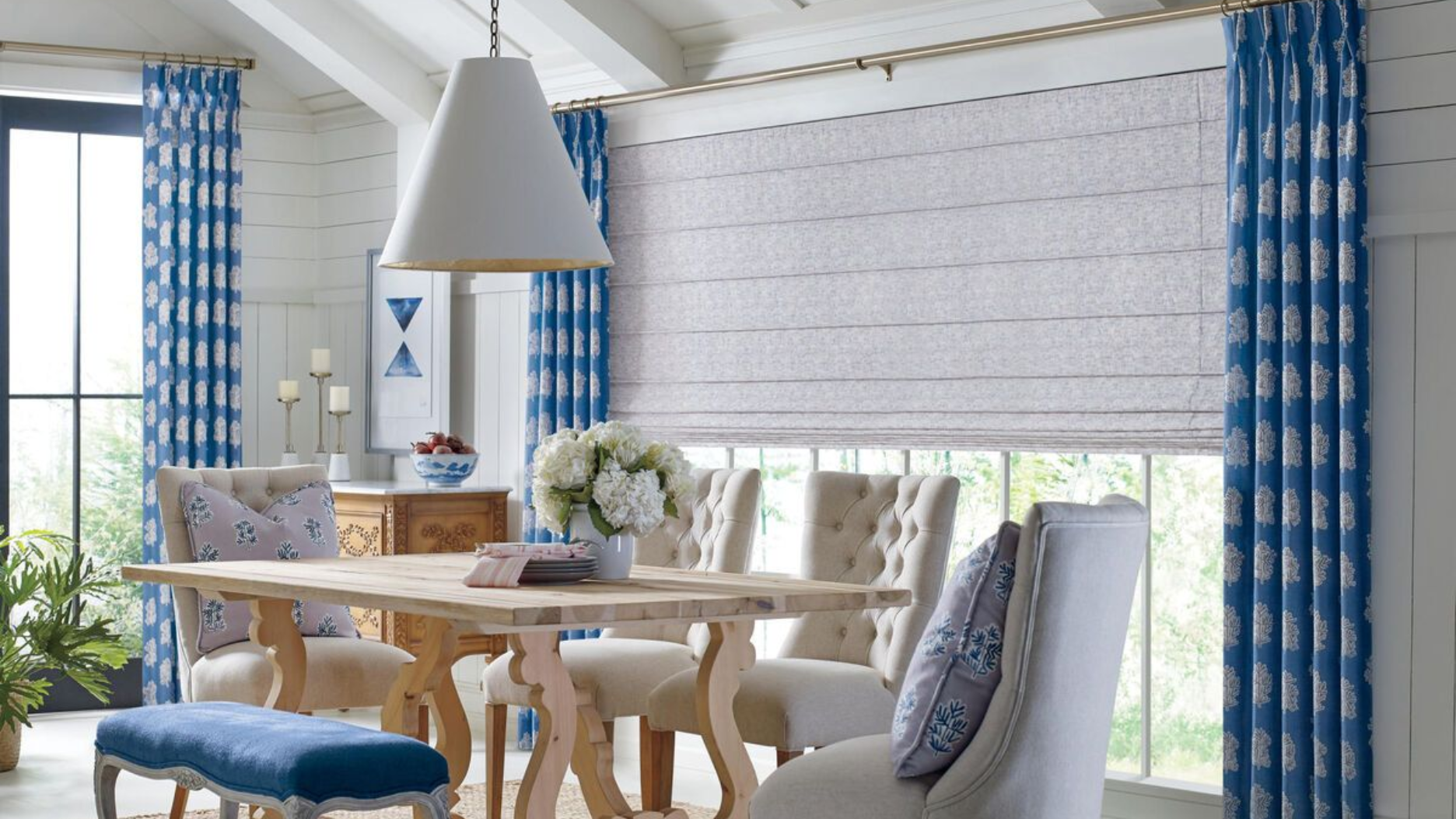Dining room with blue and white decor, wooden table, chairs, and window treatments.