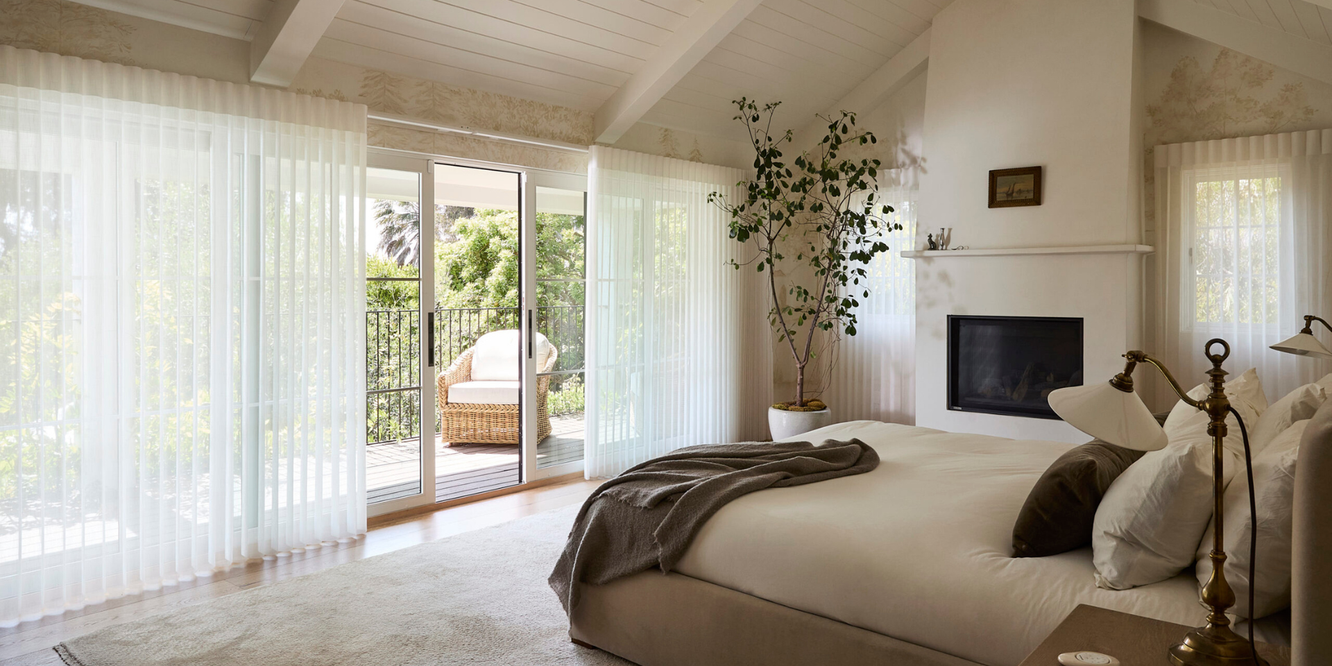 Hunter Douglas Luminette® Sheer Panels on bedroom windows and doors, illuminating it in a warm glow