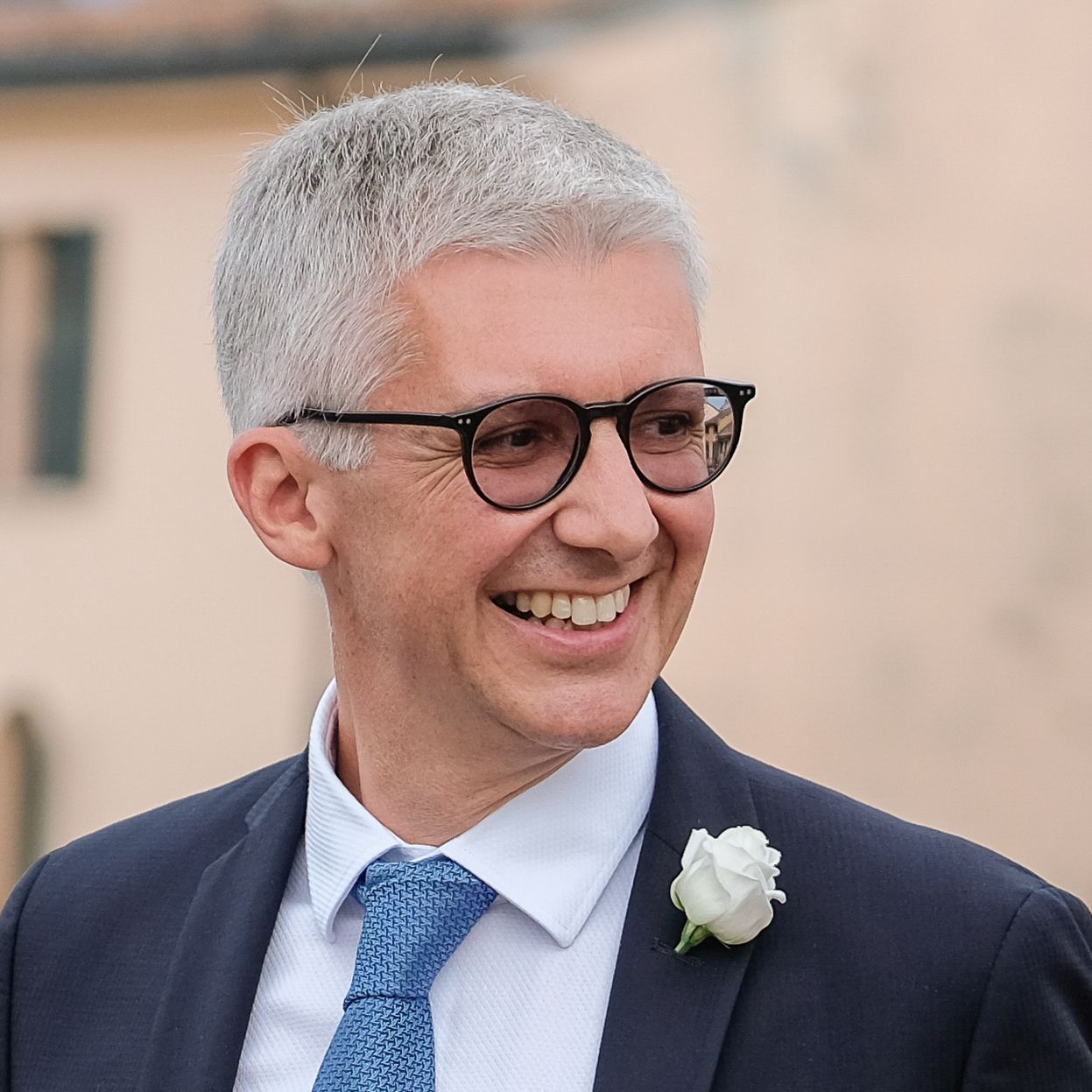 Un uomo con gli occhiali e un dolcevita nero sorride alla telecamera