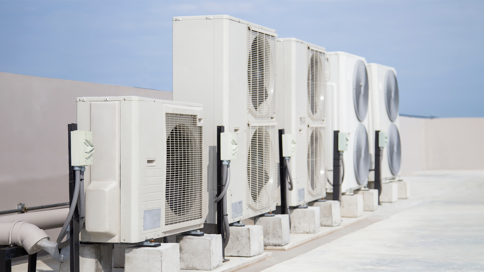 A row of air conditioners sitting on top of a building.
