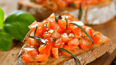 Bruschetta on toasted bread with diced tomatoes, basil, and herbs on a wooden board