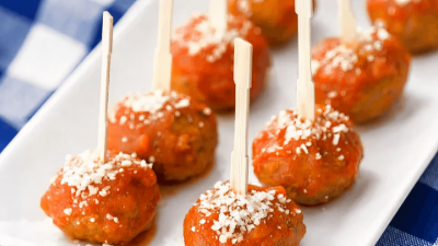 Caramelized apple pops on sticks, dusted with coconut, arranged on a white platter