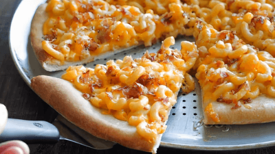 Cheese-covered pizza slices on a metal pan, one slice being lifted with a spatula