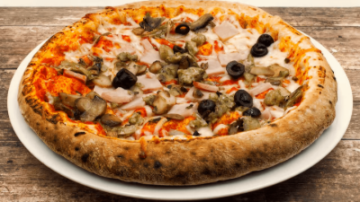 Pepperoni and vegetable pizza on a white plate with a golden crust
