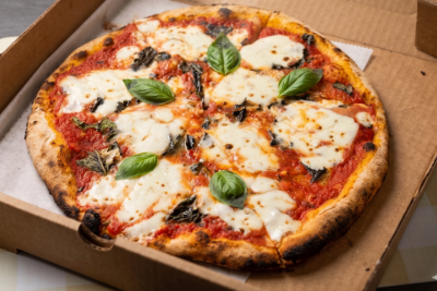Margherita pizza with basil leaves in a cardboard box