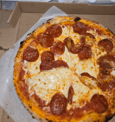 Pepperoni pizza in a cardboard box, with melted cheese and browned crust