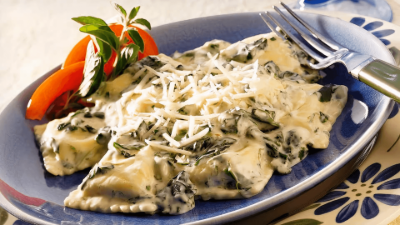 Pasta with creamy sauce and shredded cheese on a blue plate, garnished with tomato and basil