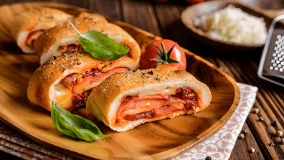 Fresh baked stuffed bread rolls with basil on a wooden board, served with grated cheese