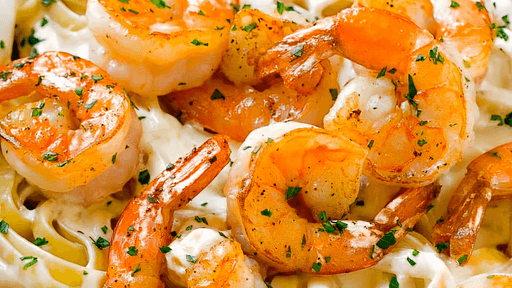 Close-up of shrimp pasta with creamy sauce, orange shrimp, and herbs