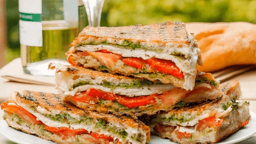 Stacked vegetable sandwiches on a plate with olive oil bottles in the background