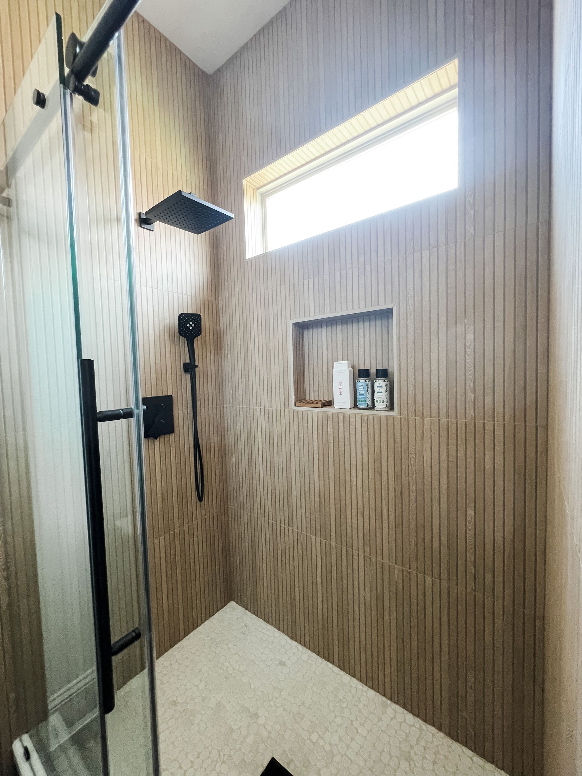 A bathroom with a sliding glass shower door and a window.