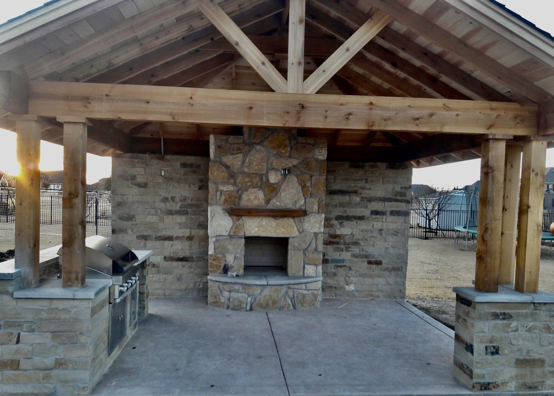 A large stone fireplace under a wooden roof
