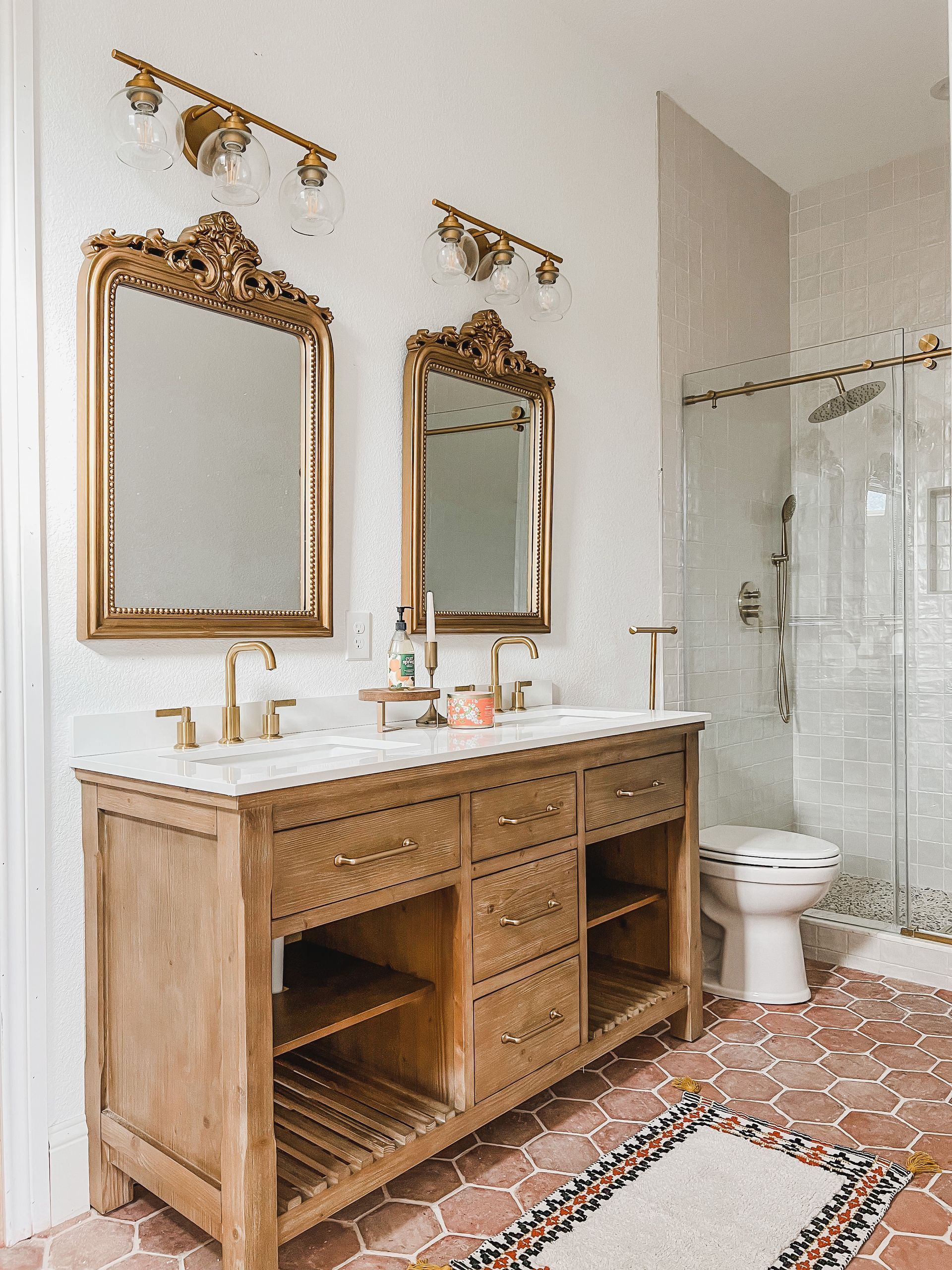 A bathroom with two sinks , two mirrors and a toilet.