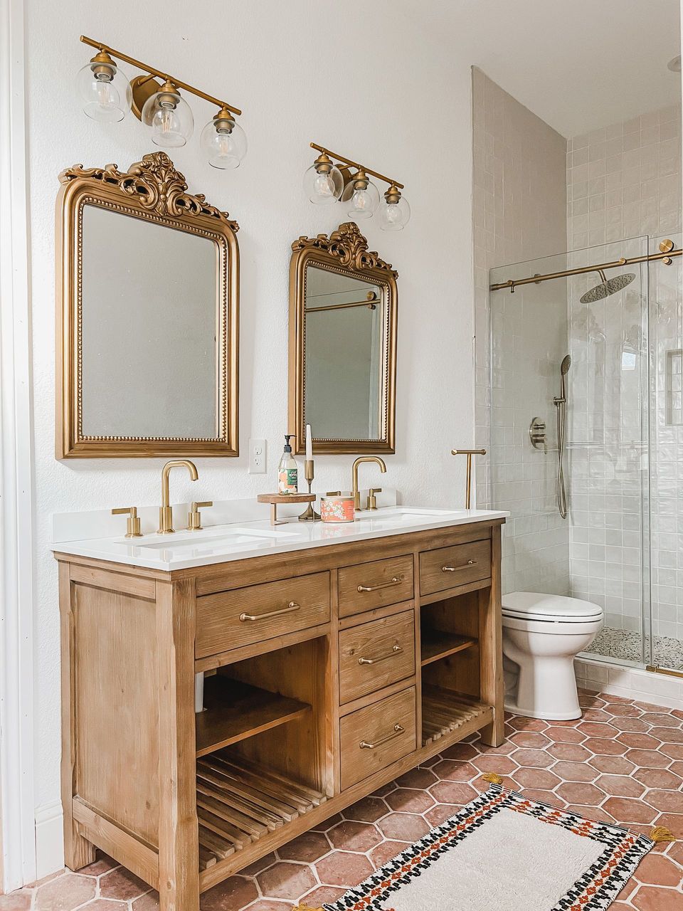 A bathroom with two sinks , two mirrors and a toilet.