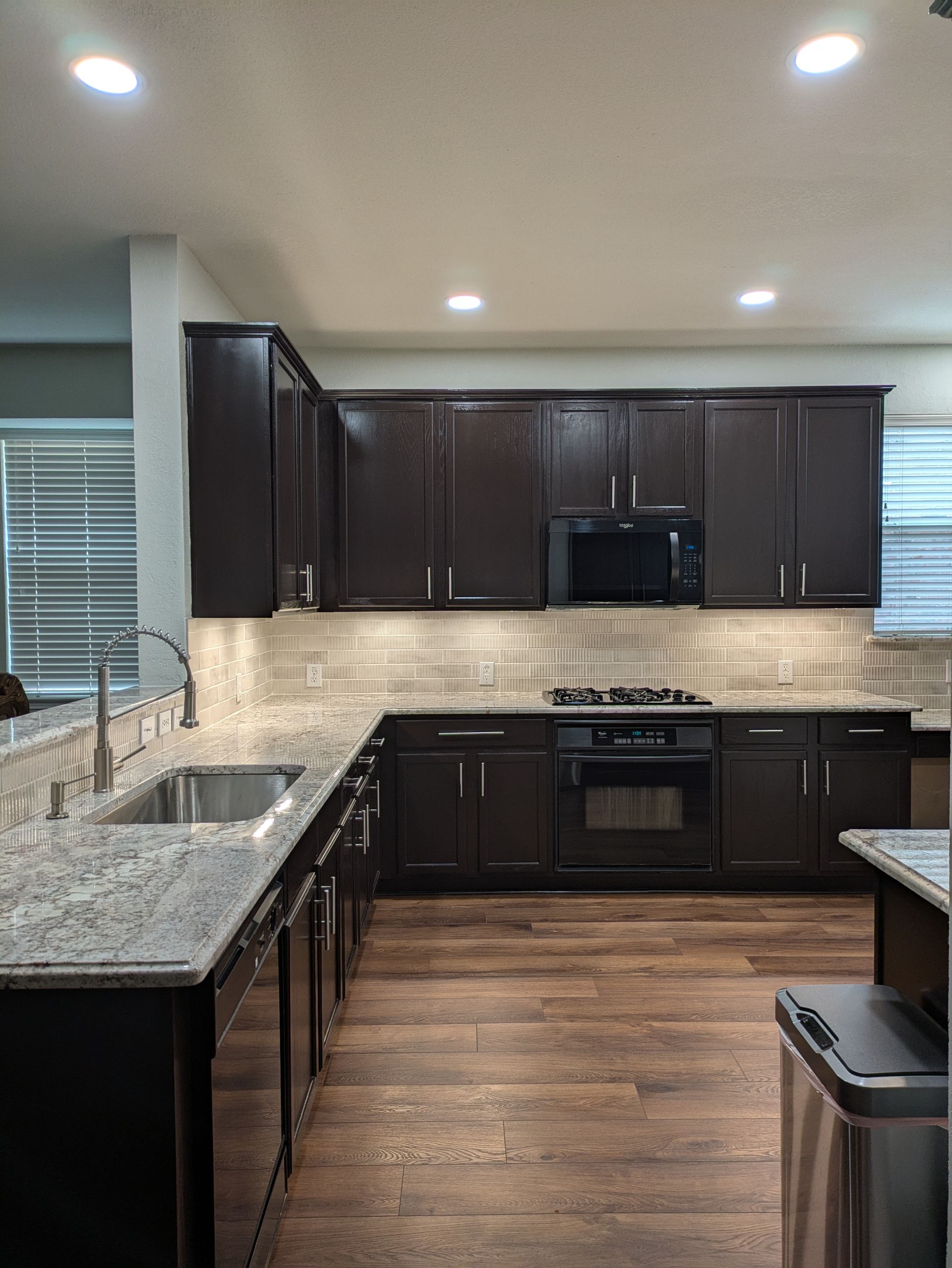 Dark brown kitchen cabinets, granite countertops, stainless steel appliances, and wood flooring.