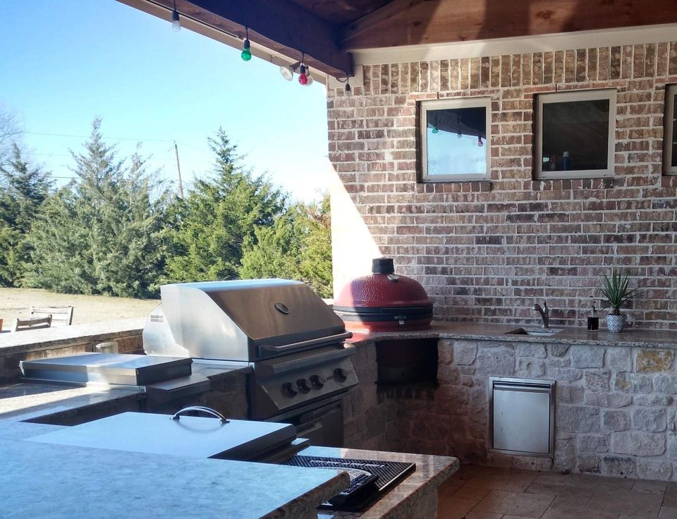An outdoor kitchen with a brick wall and a grill