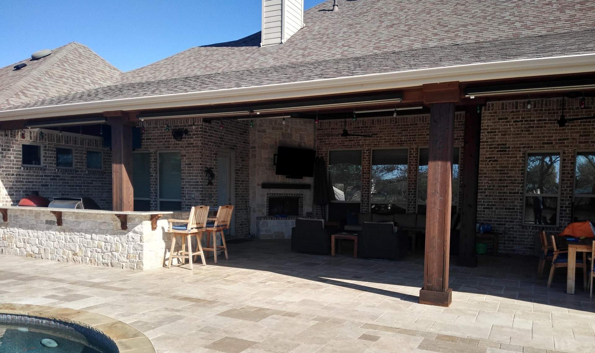 A car is parked in front of a large brick house with a covered patio.