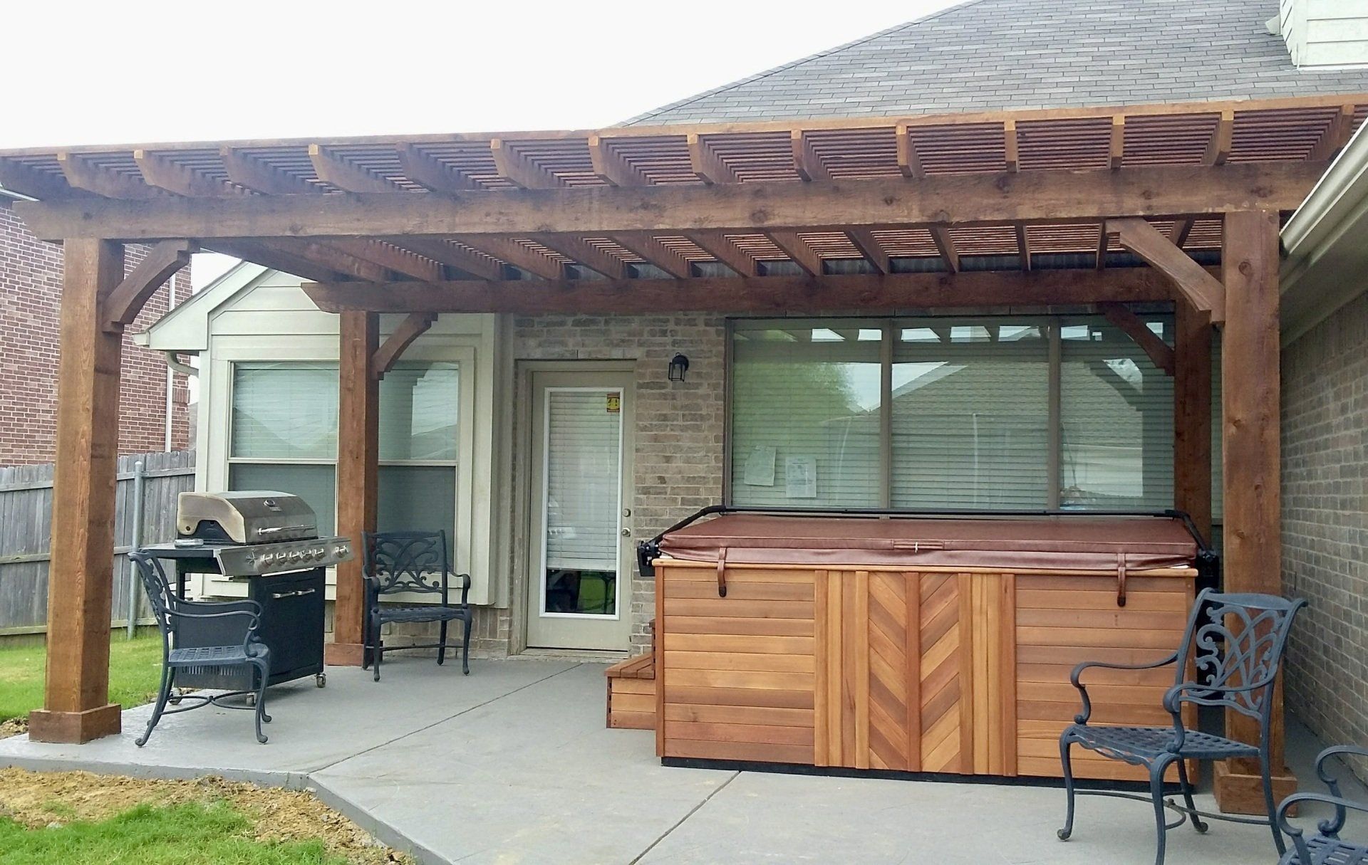 A wooden pergola with a hot tub underneath it