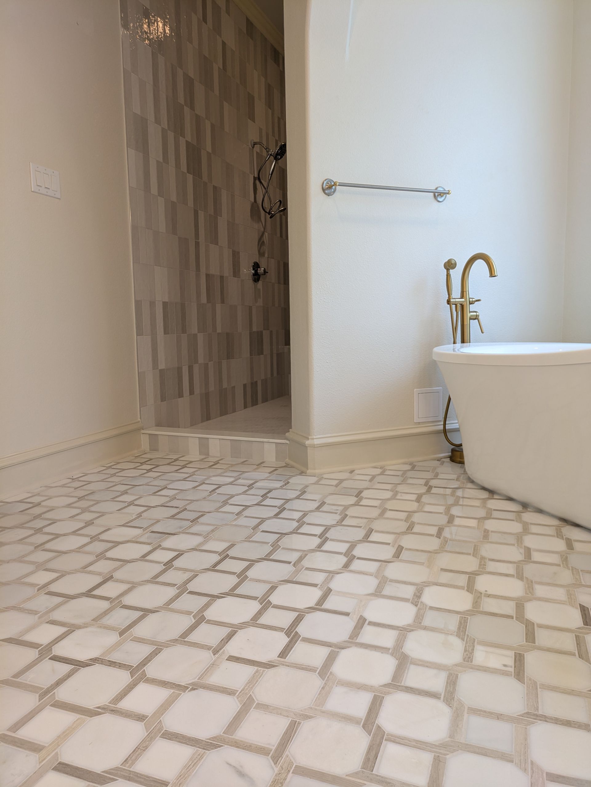 Bathroom with patterned tile floor, walk-in shower, and freestanding tub.