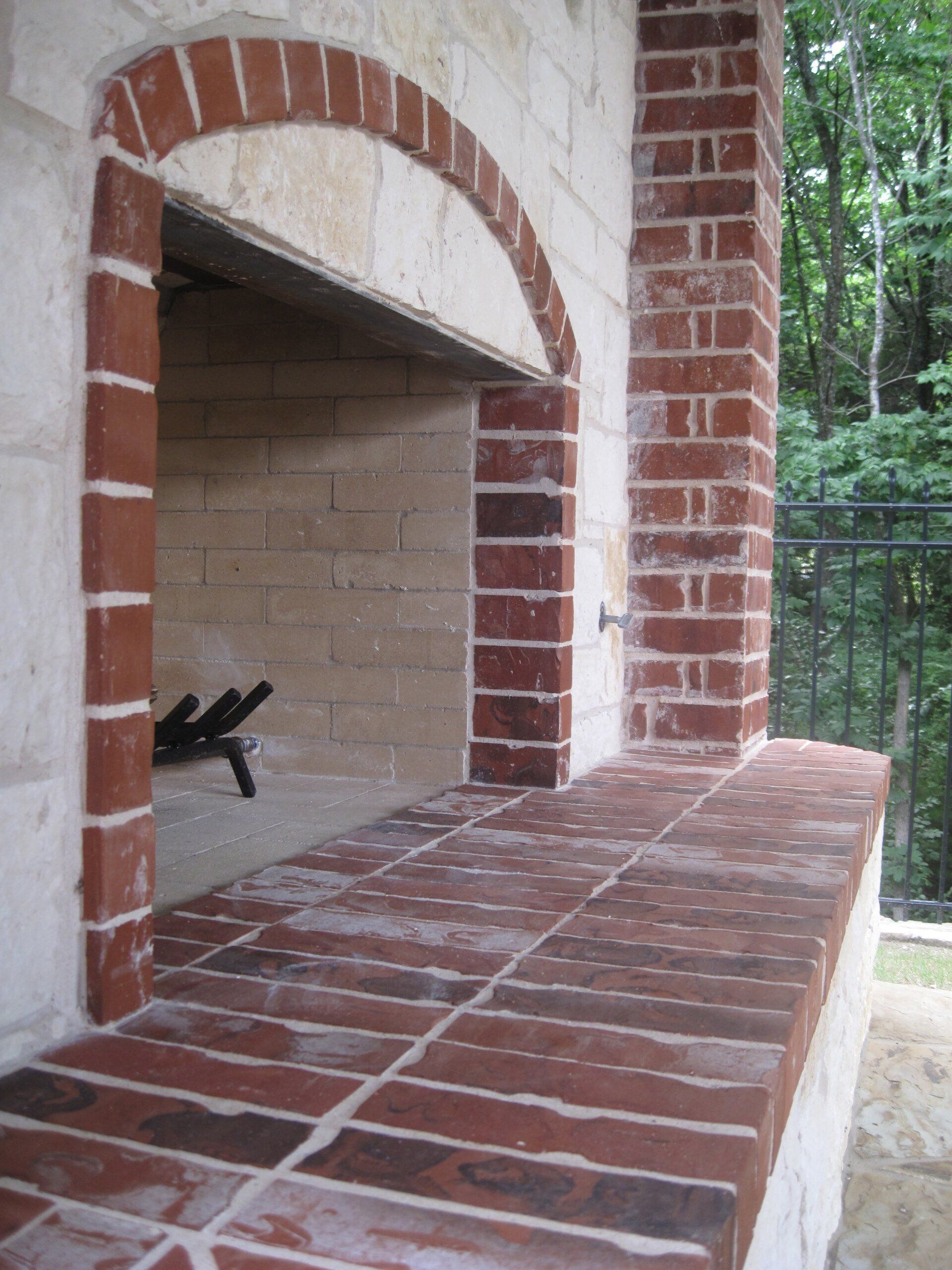 A brick fireplace with a stone wall behind it