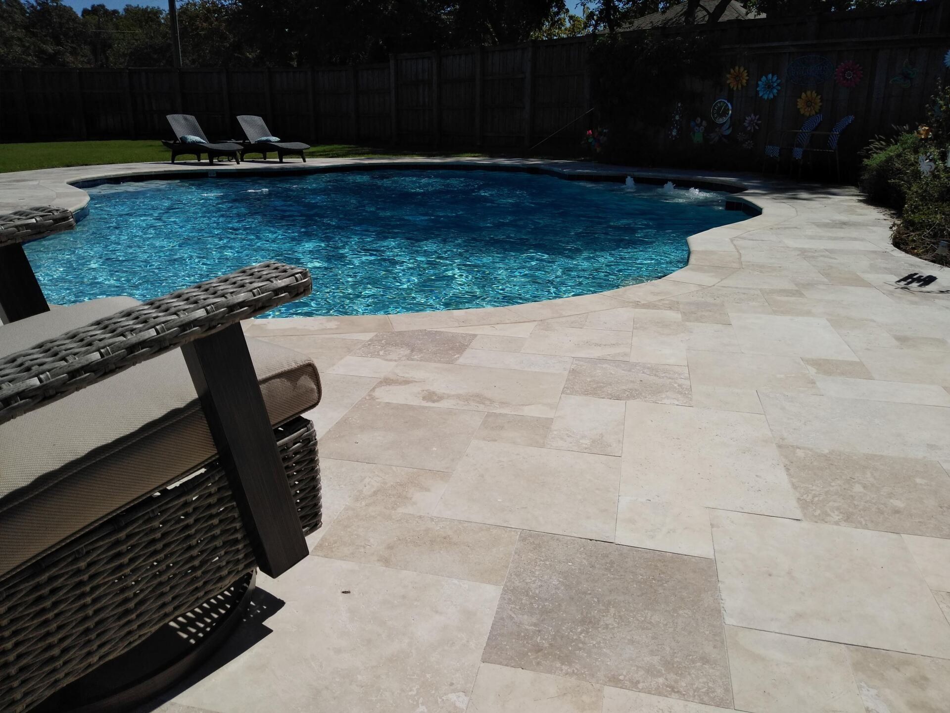 A large swimming pool surrounded by chairs and a fence