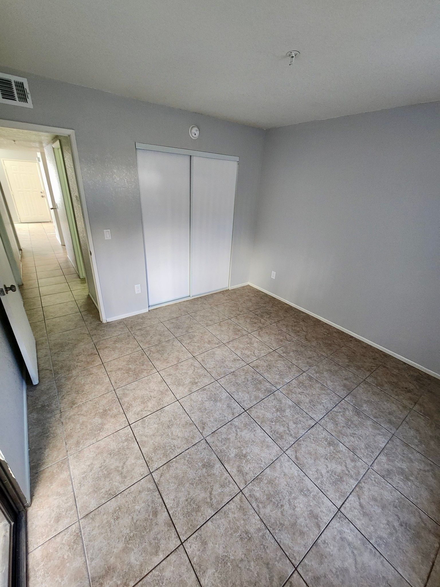 An empty room with a tiled floor and a closet.