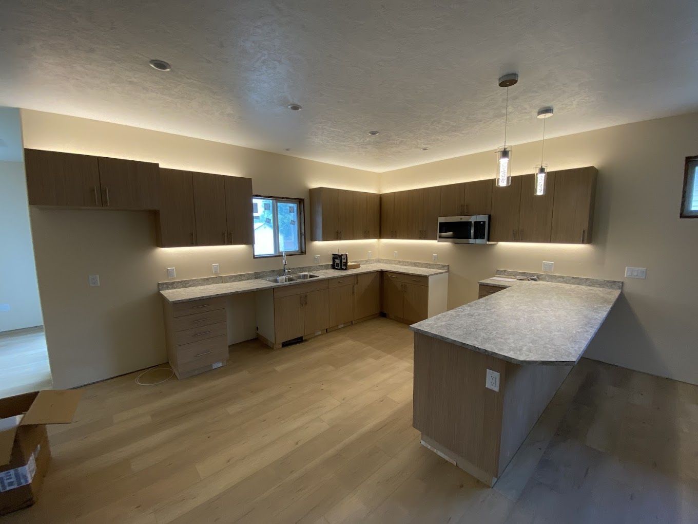 A kitchen with wooden cabinets , granite counter tops , and a microwave.