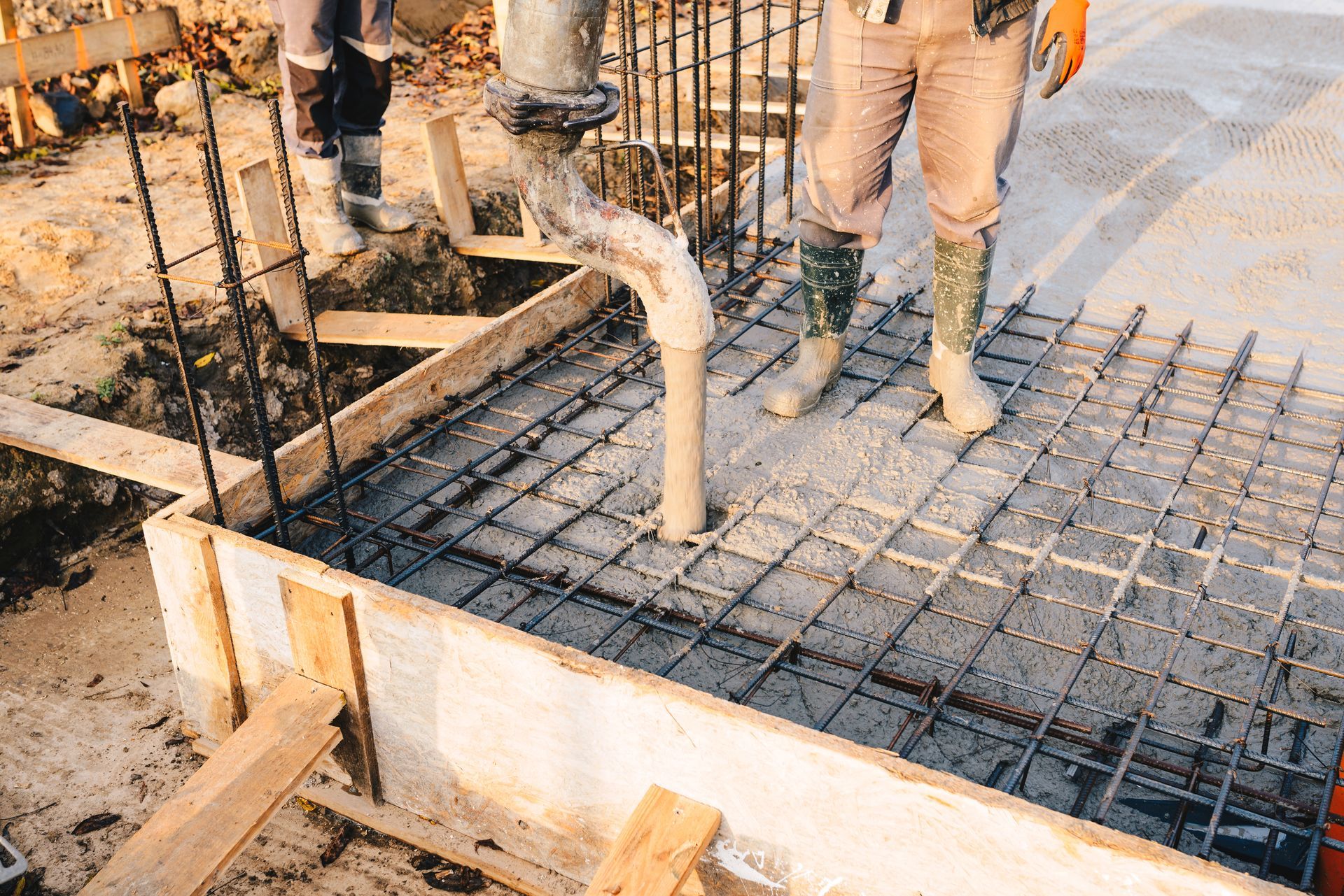 Construction workers pouring concrete over rebar at a building foundation