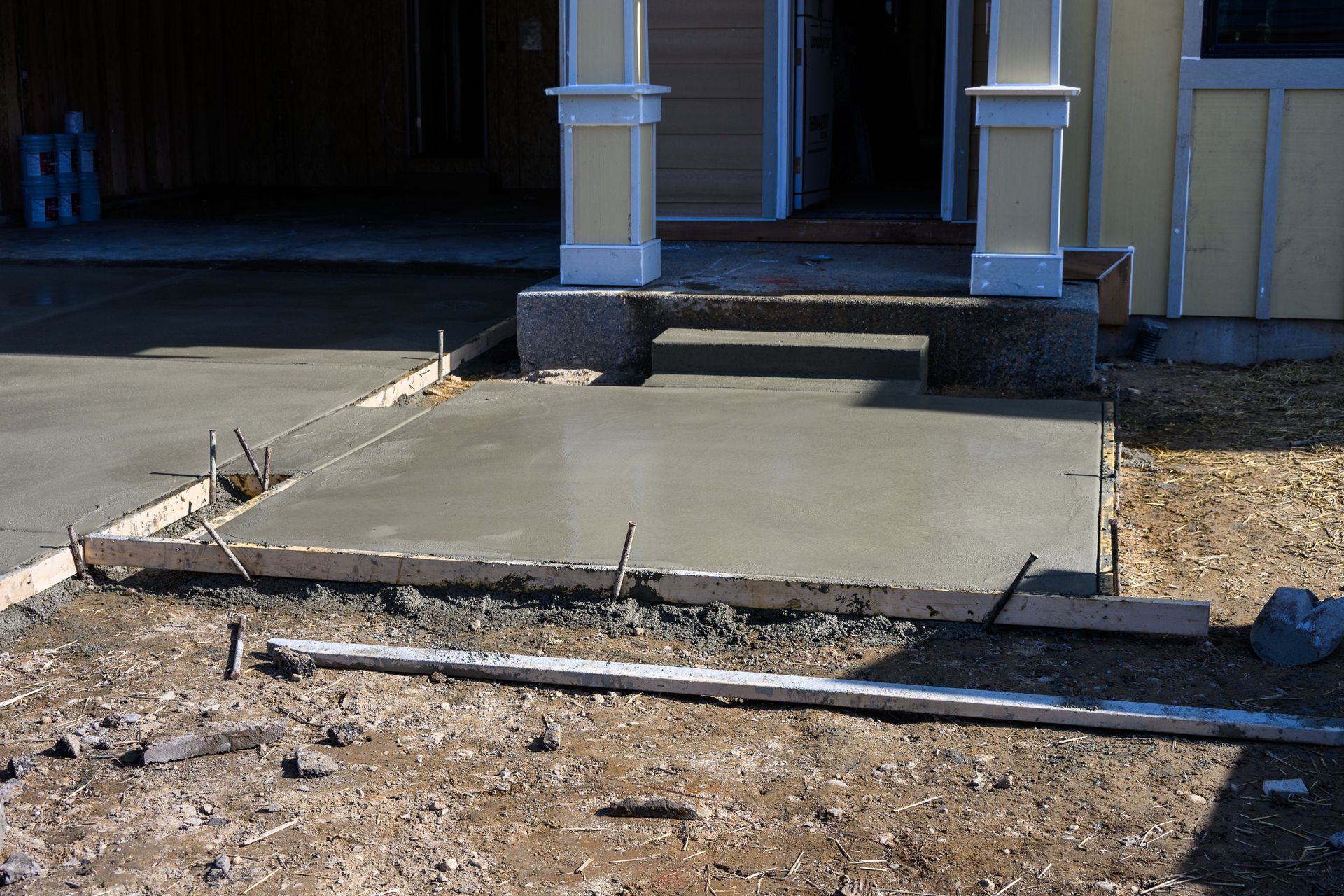 Concrete front porch ramp under construction with exposed dirt and steps leading to a house entrance Concrete front porch ramp under construction with exposed dirt and steps leading to a house entrance