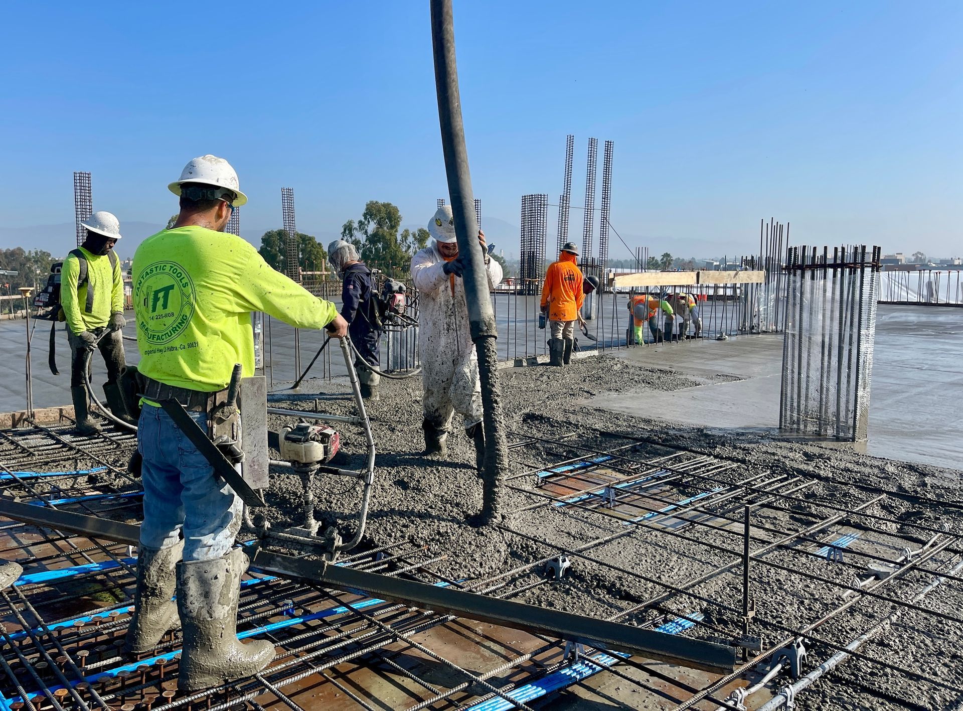 Workers pouring concrete on a rebar construction site under a clear blue sky Workers pouring concrete on a rebar construction site under a clear blue sky