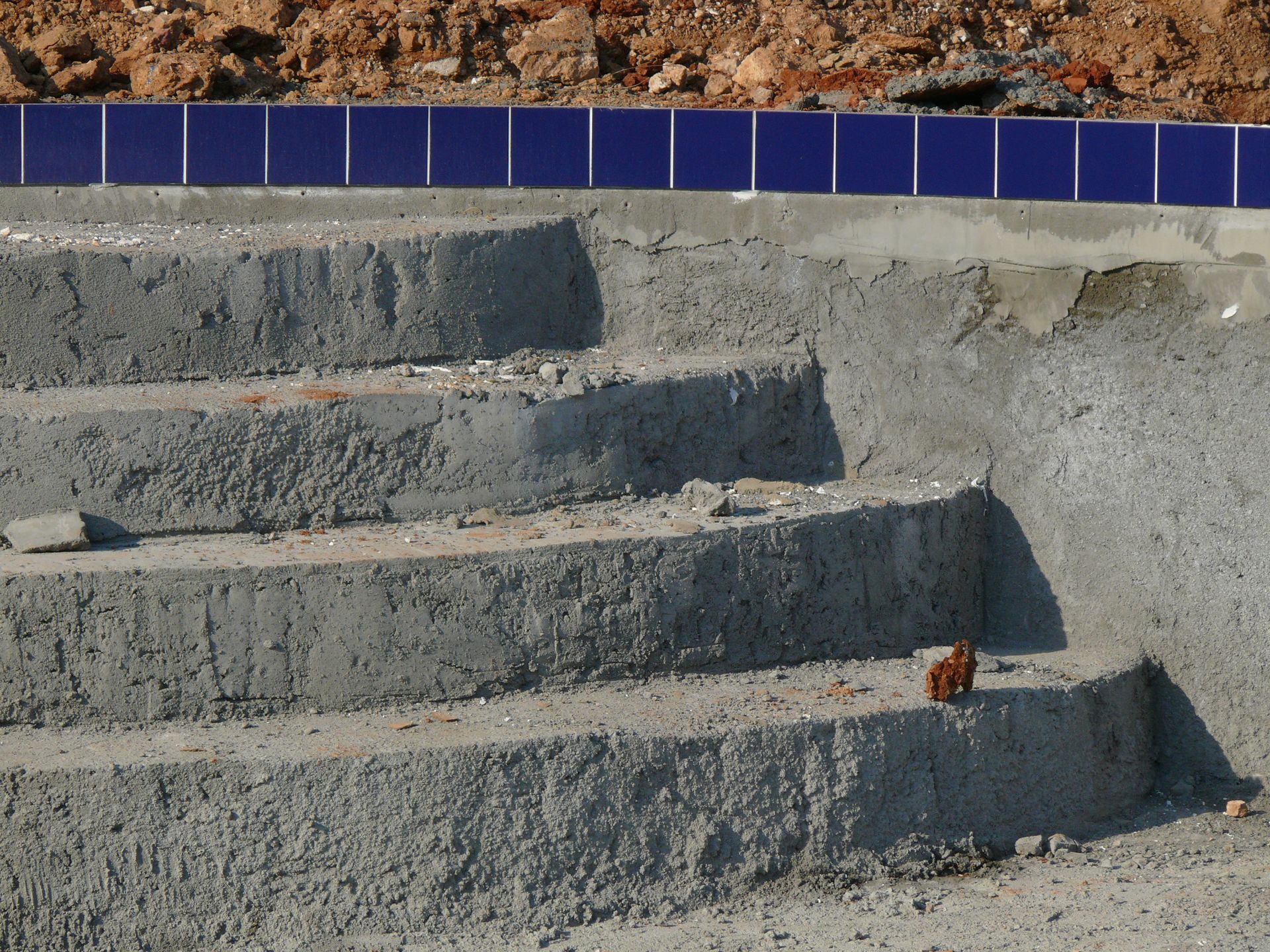 Concrete steps with blue tile border leading up a rocky embankment