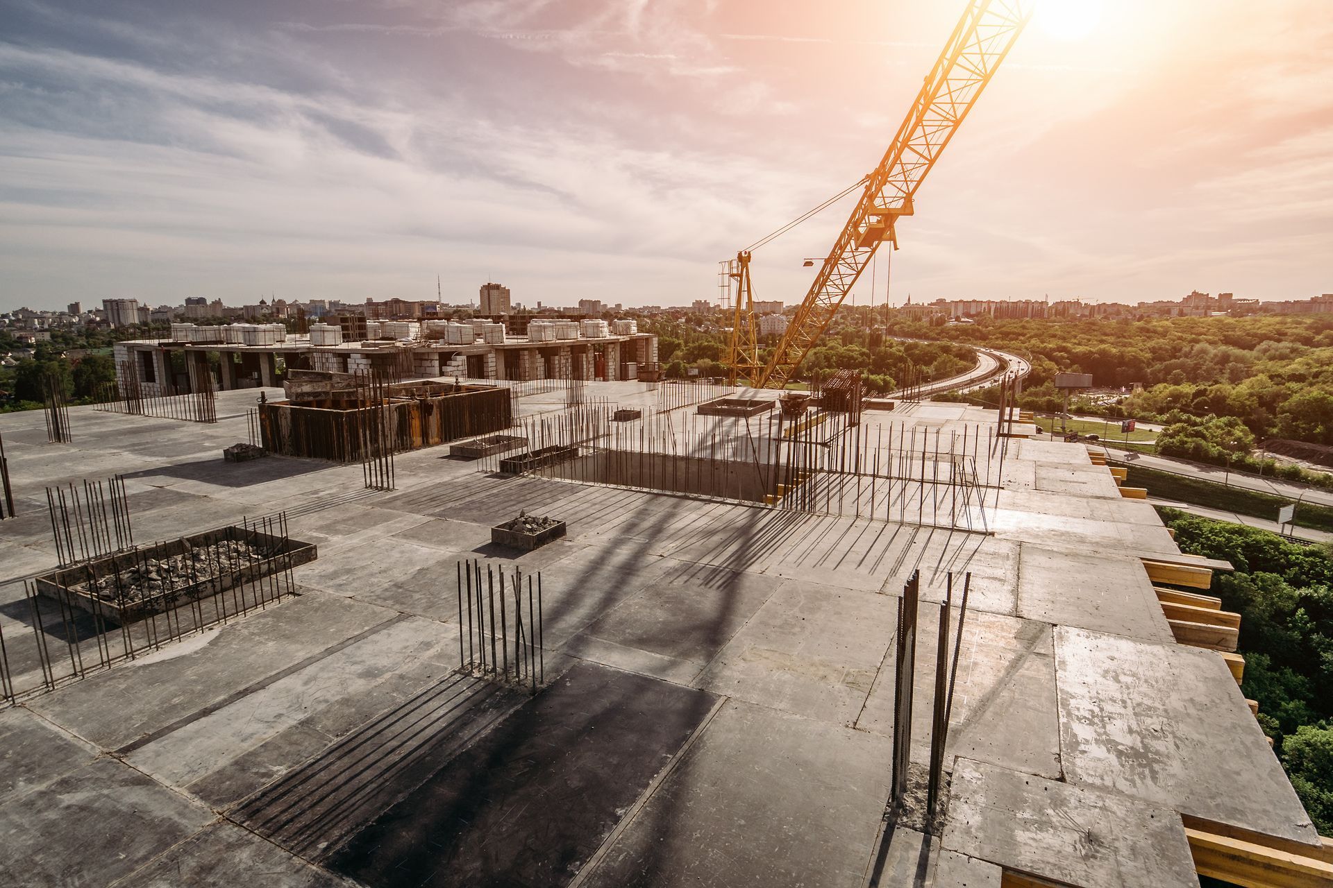 Concrete construction site with crane at sunset and wet foundation slabs