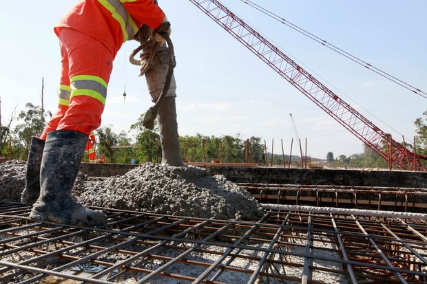 Construction worker pouring concrete onto steel rebar at a building site