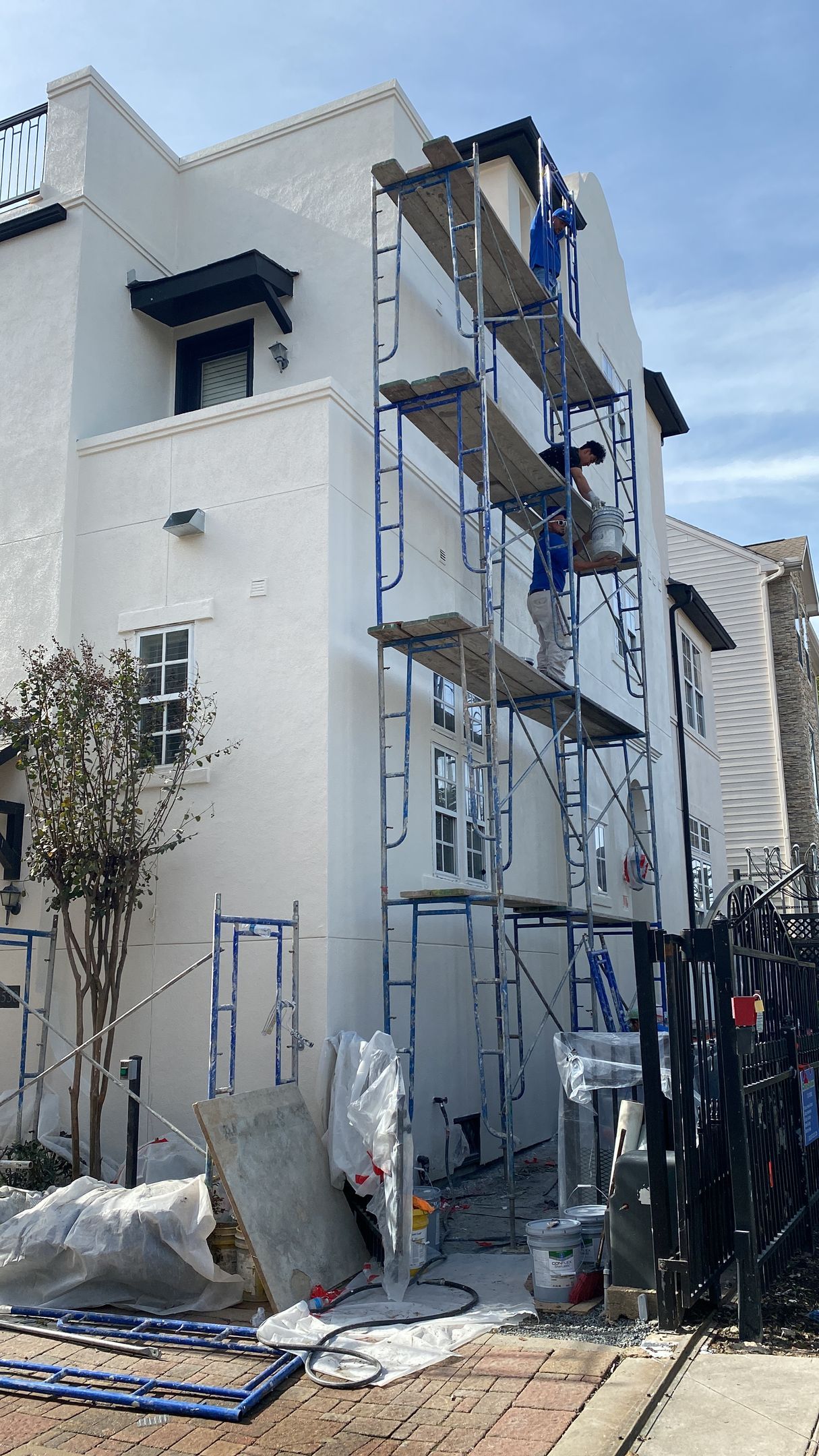 A white building is being painted with scaffolding around it.