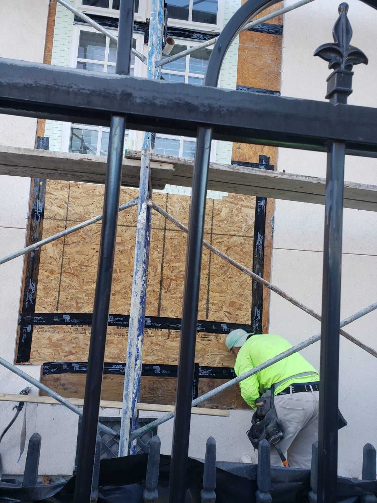 A man in a neon green jacket is working on a building