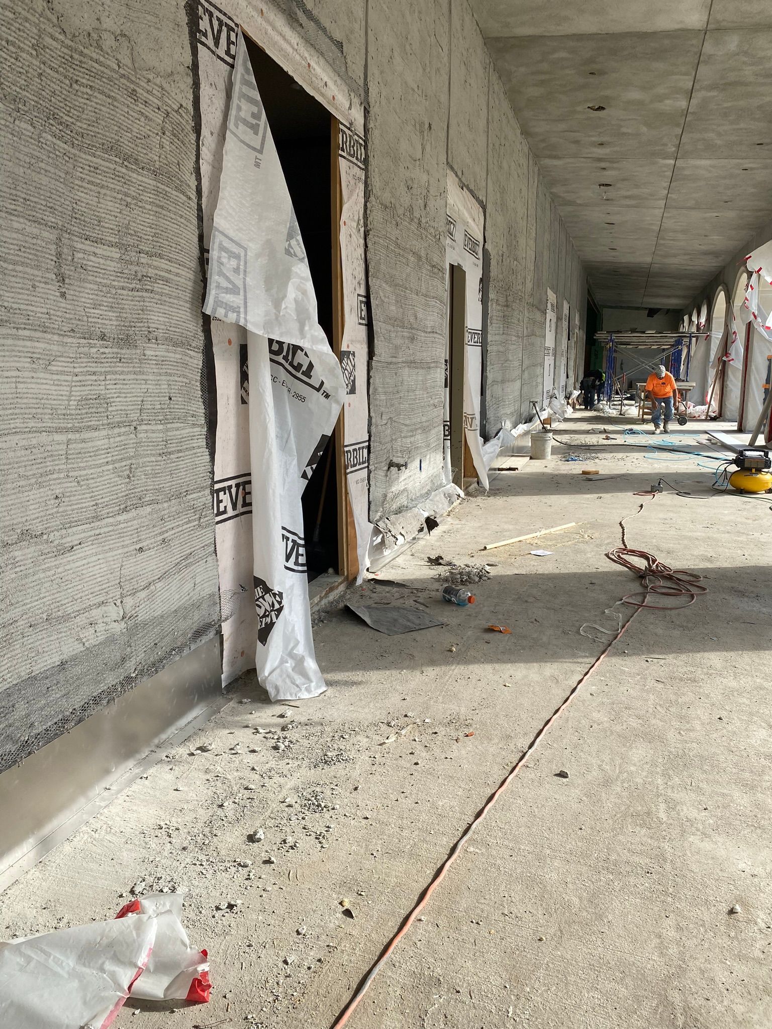 A long hallway in a building under construction with a broken door.