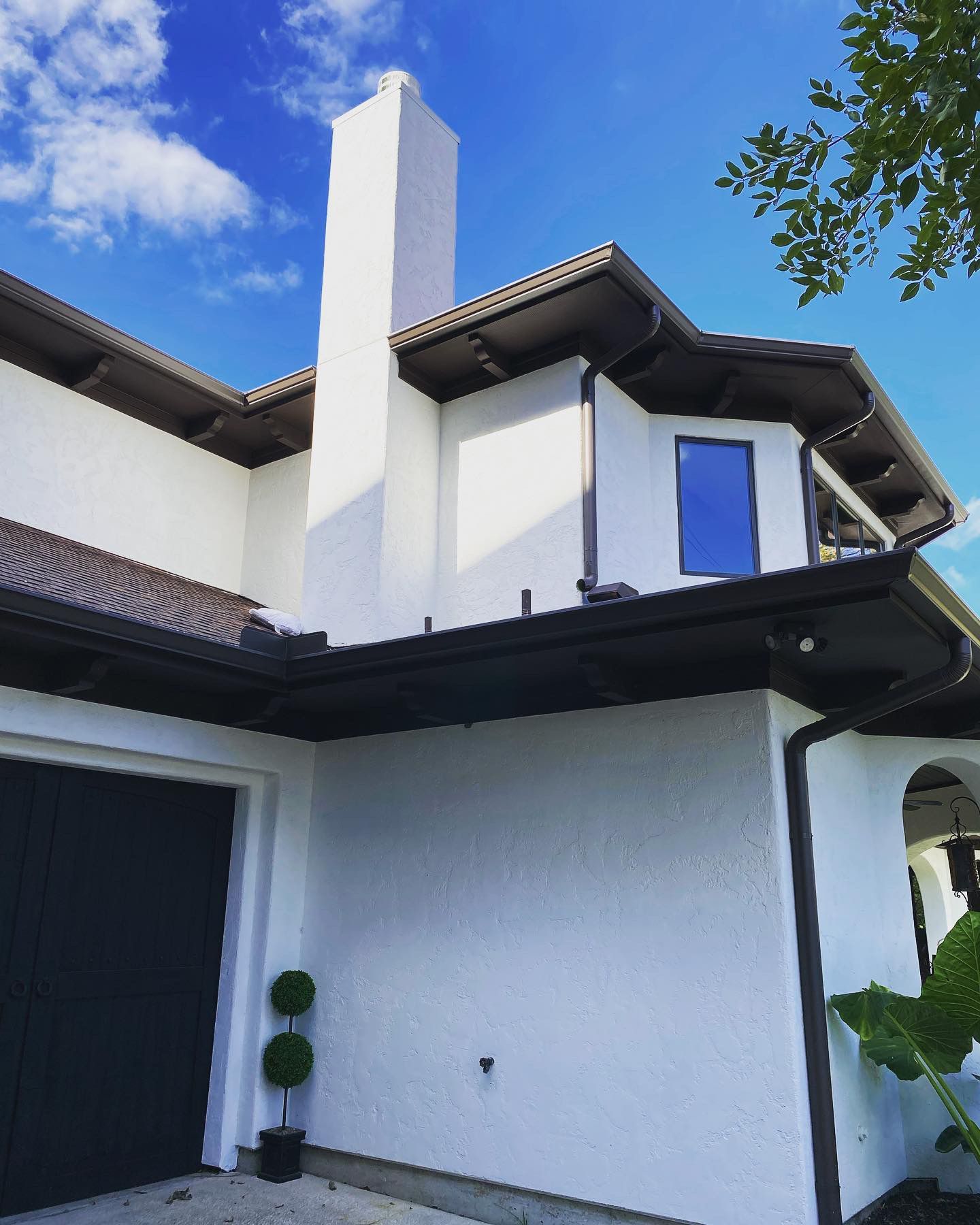 A white house with a black garage door and a chimney
