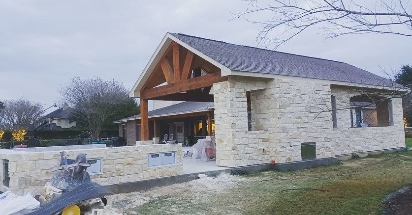A large stone house with a wooden roof is being built.