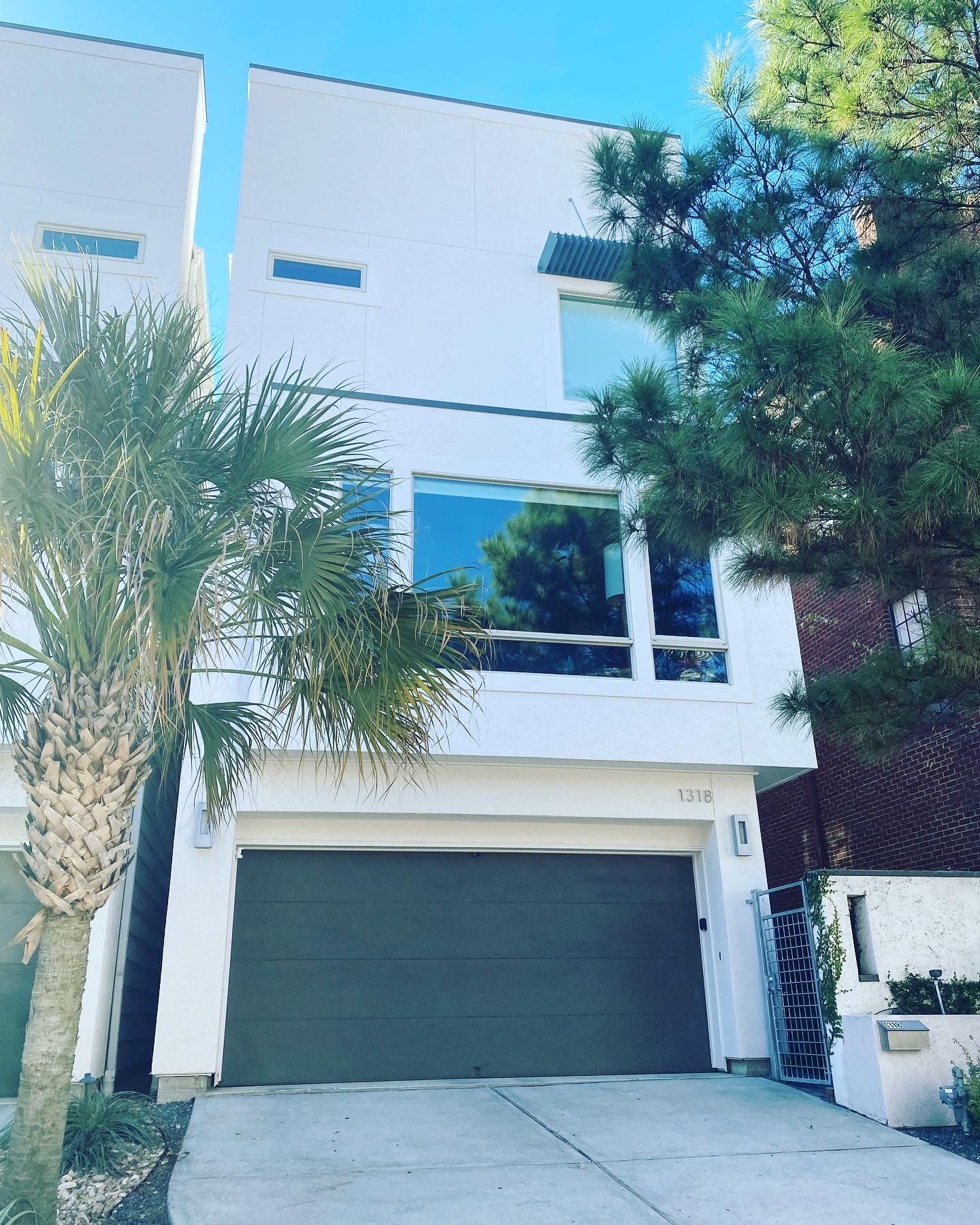A white house with a garage and palm trees in front of it