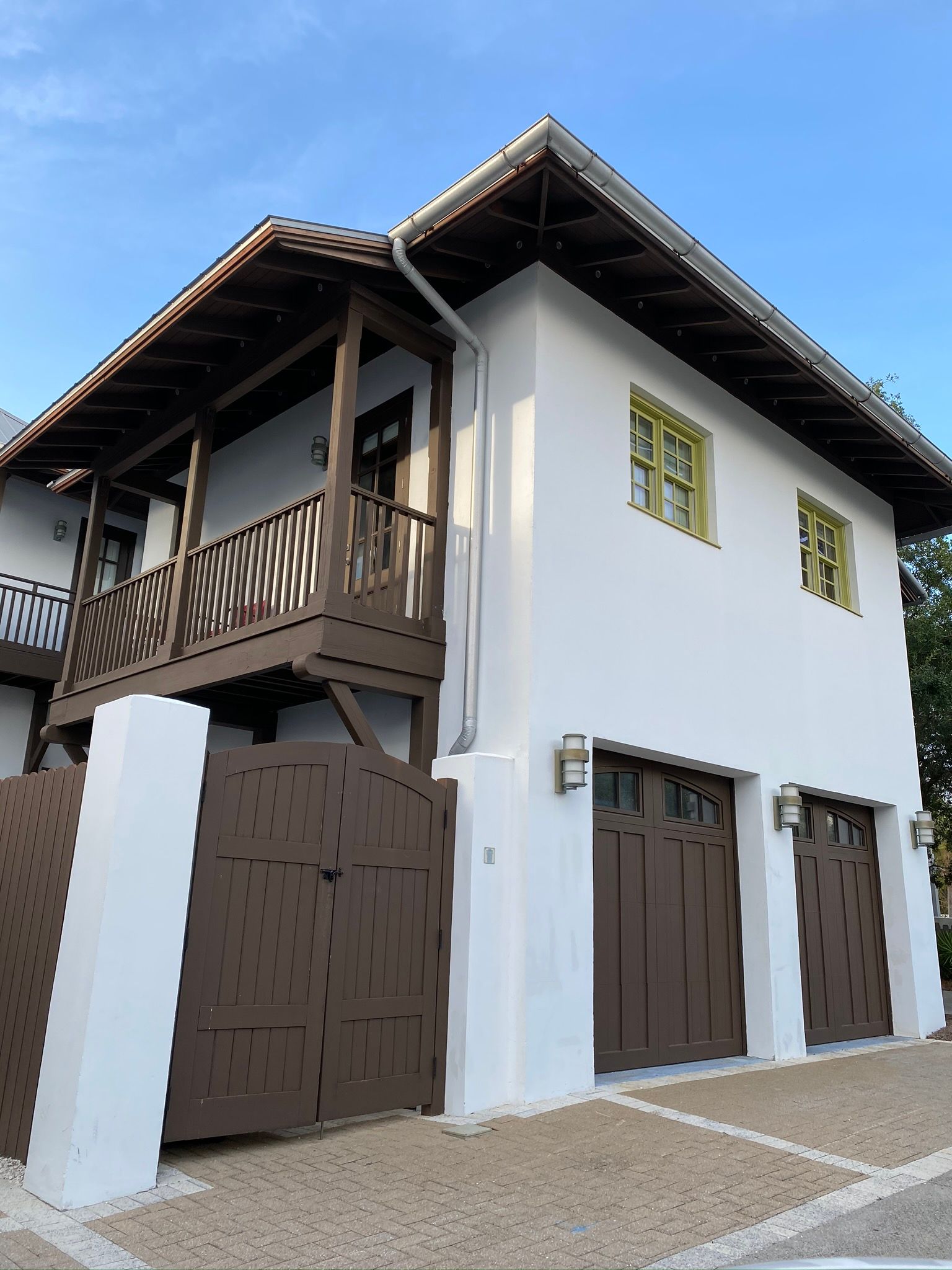 A white house with brown garage doors and a balcony