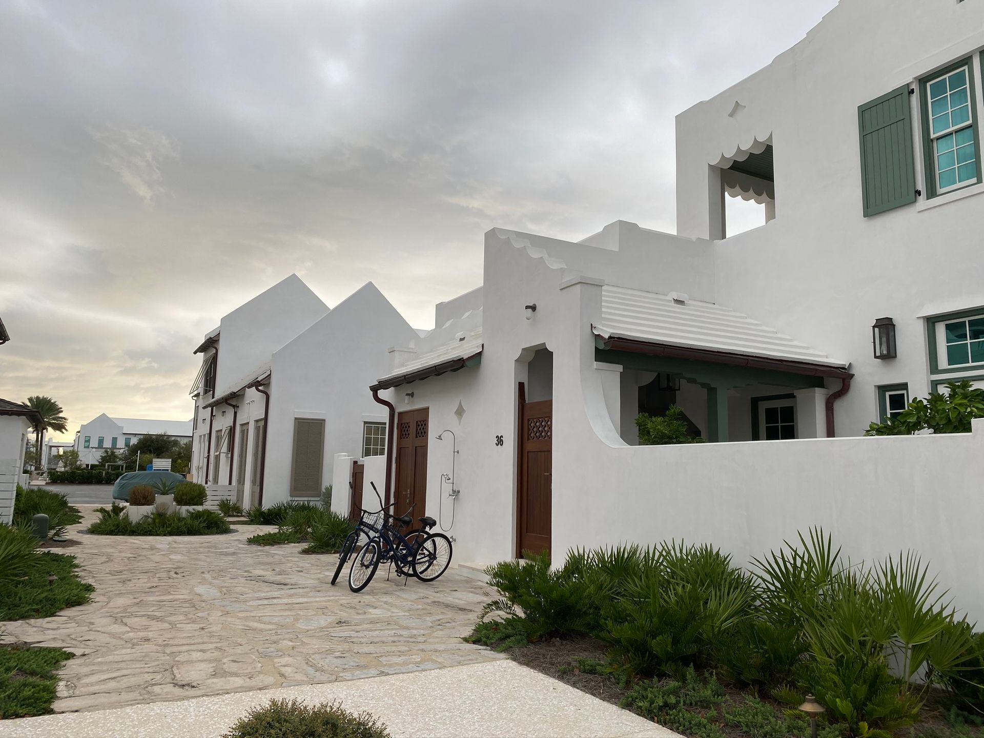 Two bicycles are parked in front of a white building