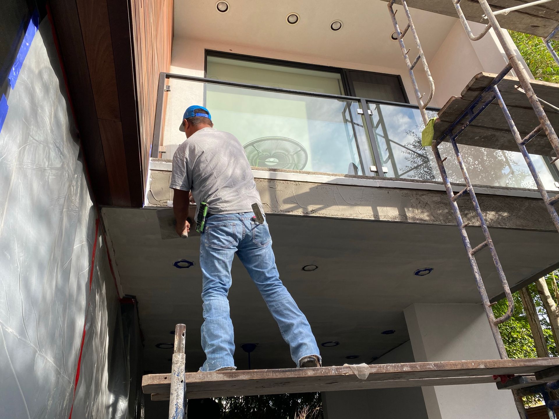 A man is standing on a scaffolding in front of a building.