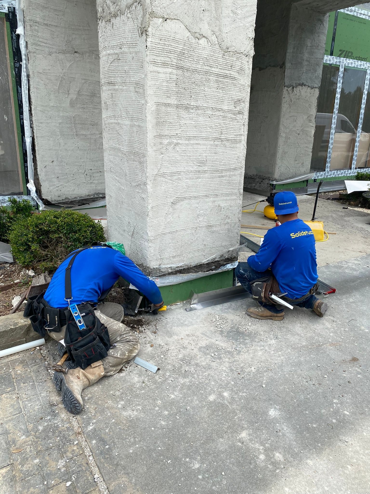 Two men are kneeling on the ground in front of a building.