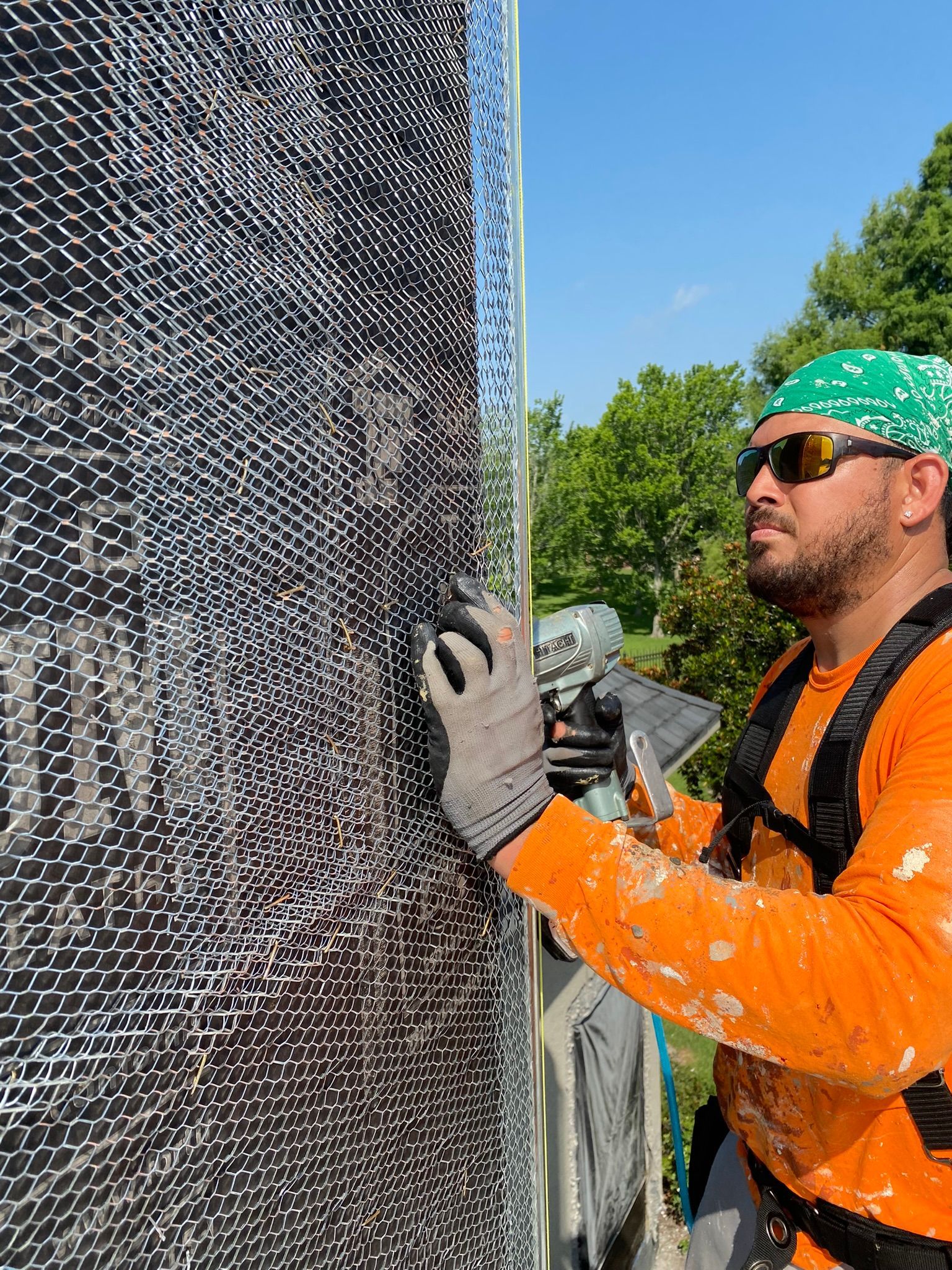 A man wearing sunglasses and a bandana is working on a wall.