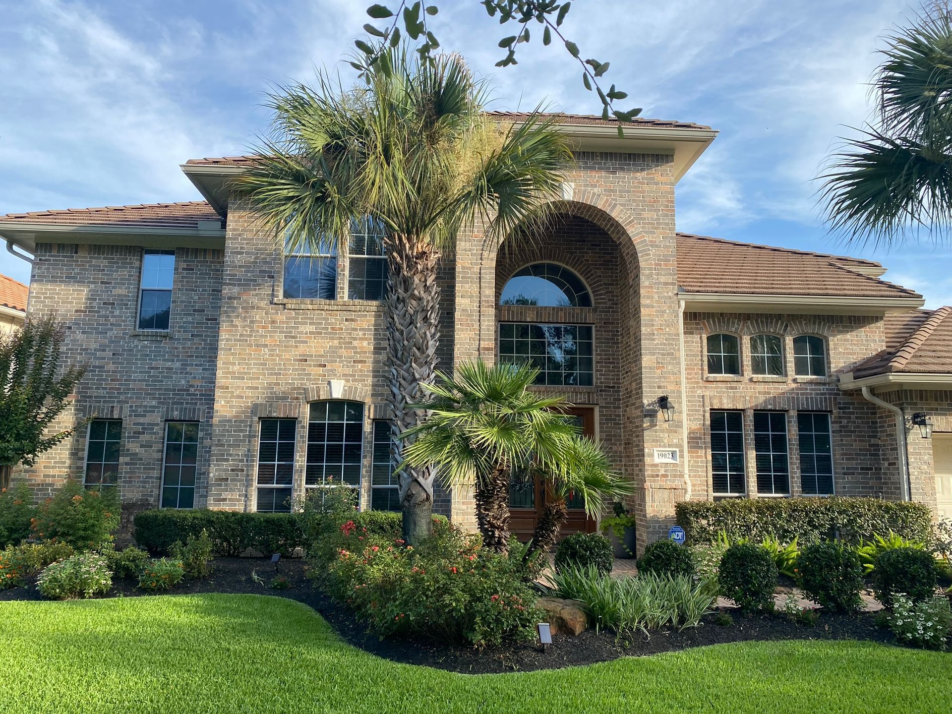 A large brick house with a palm tree in front of it