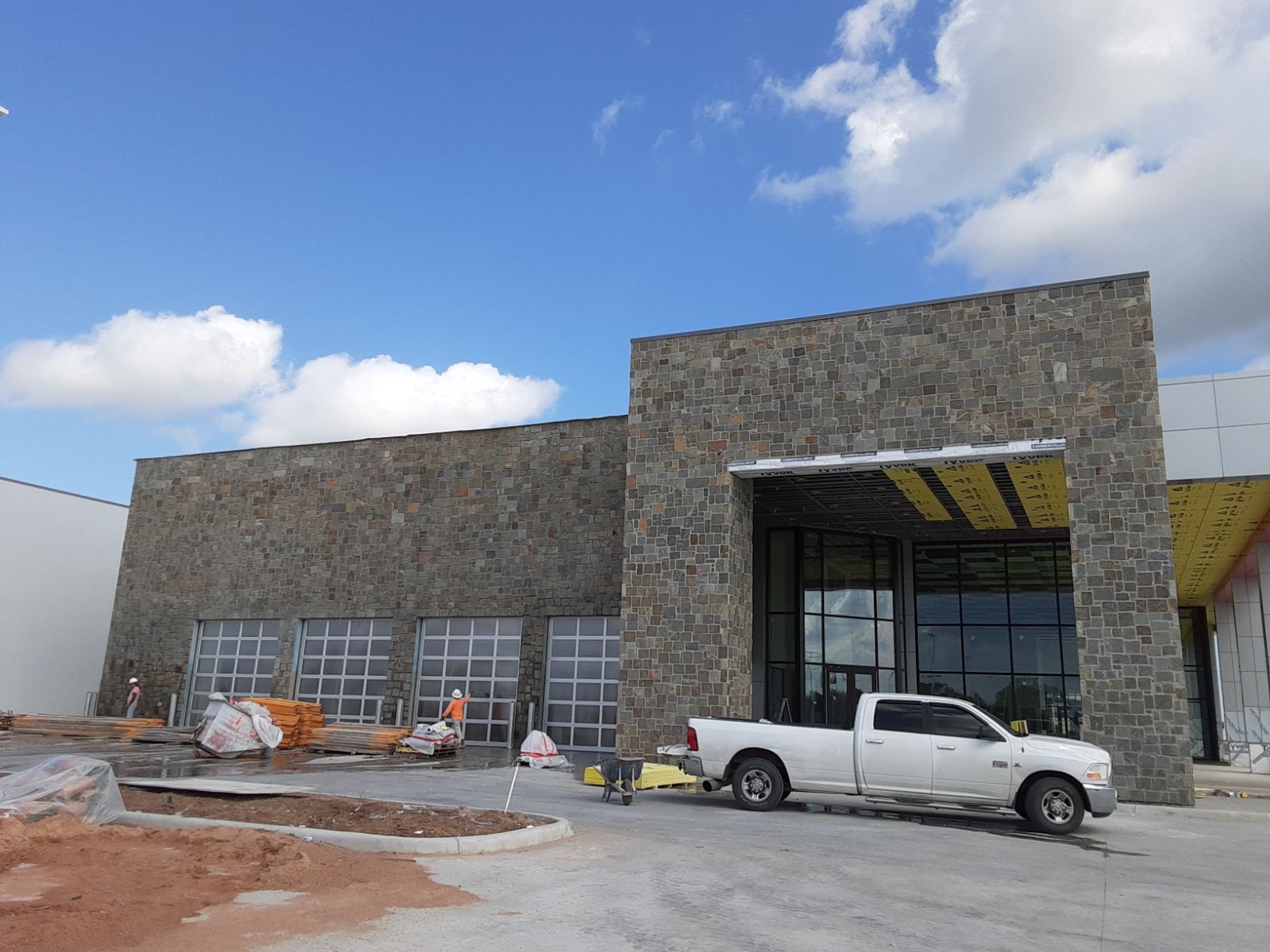 A white truck is parked in front of a building under construction.
