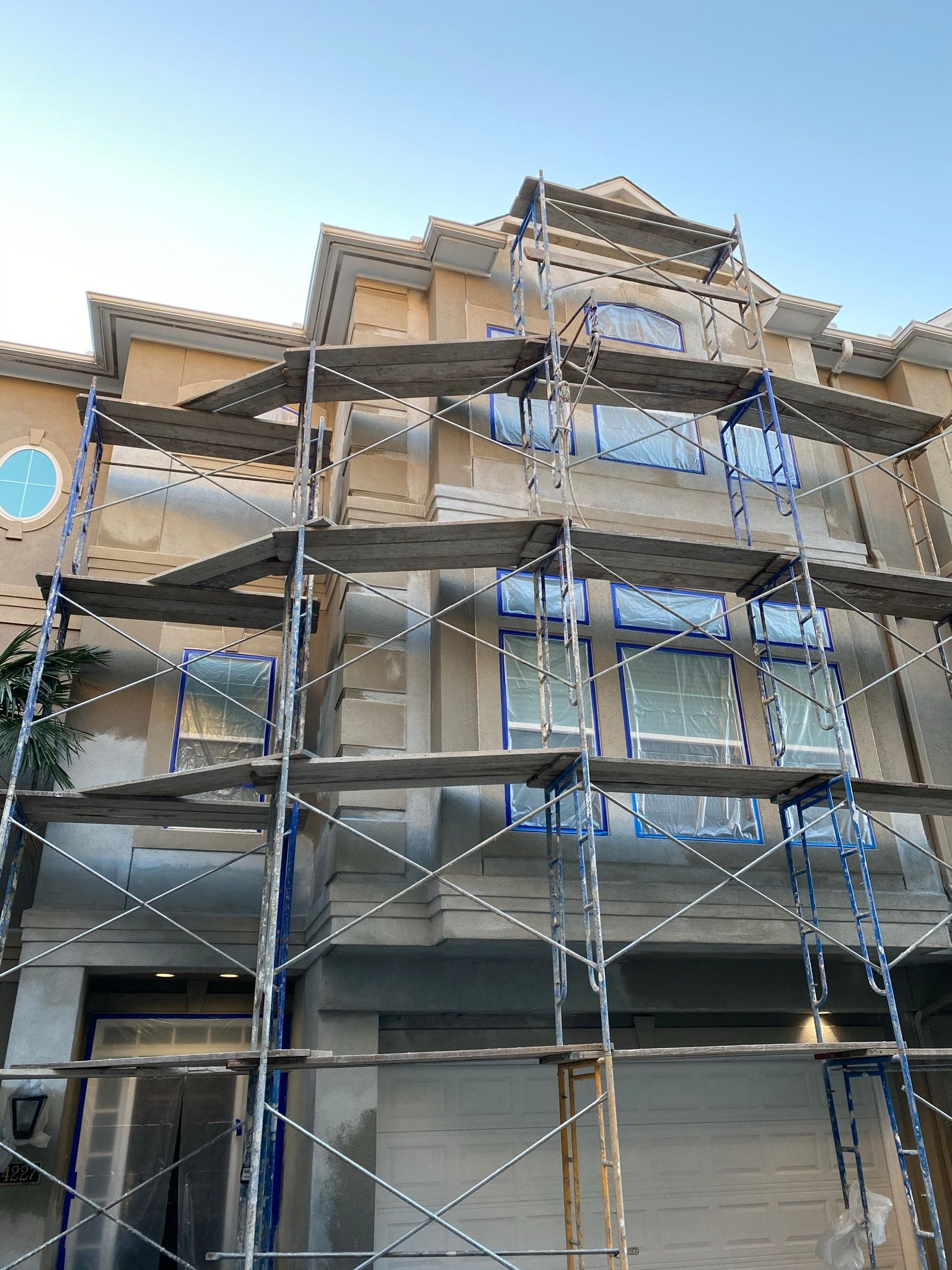A large building with scaffolding around it is being painted.